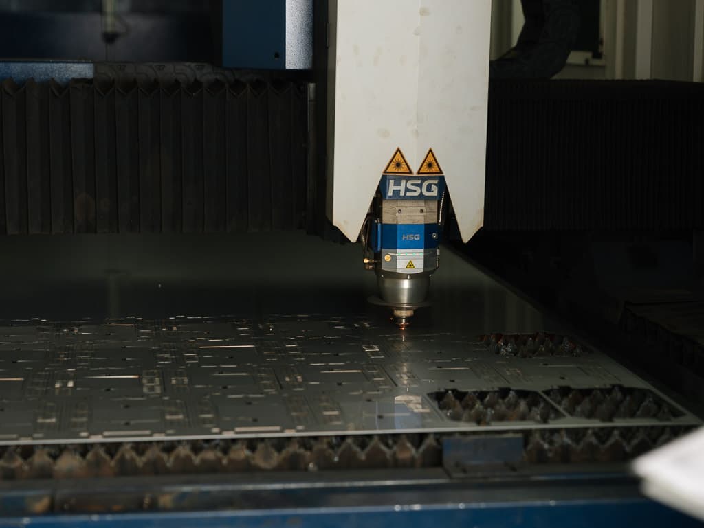 Fiber laser cutting head cutting sheet metal with sparks at Foxtron Engineering