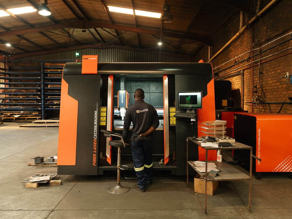 Foxtron Engineering operator running the fiber laser cutter at the Centurion workshop