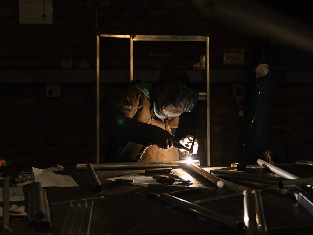 Welding a steel tube frame under spotlight at the Foxtron Engineering assembly bench