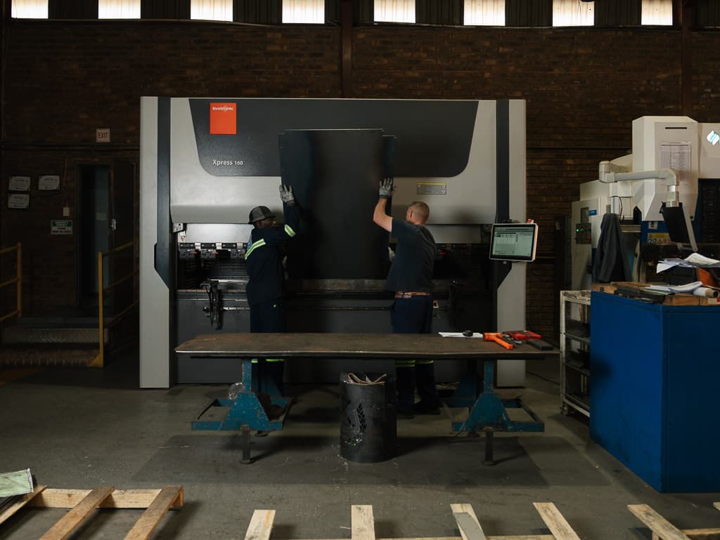Operators folding a large sheet metal panel on a Bystronic CNC press brake